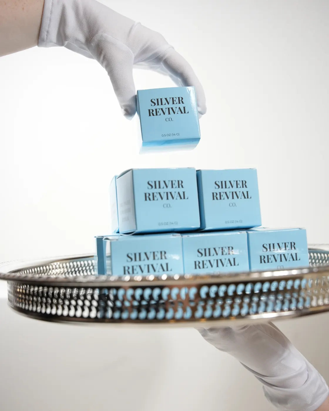 A gloved hand holding a silver tray